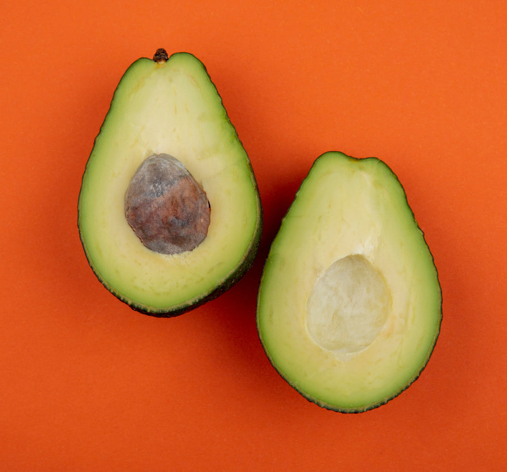 Orange Backdrop with a halved avocado, top down view